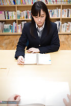 Student reading book in library wearing uniform