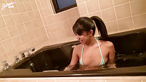 Satsuki sitting in bathtub hair in ponytail wearing green bikini