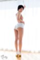 Standing at curtained window looking back short hair wearing shorts high heels