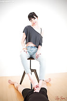 Stroking cock between her bare feet wearing jeans