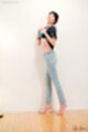 Standing against wall wearing jeans bare feet