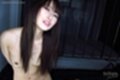 Arms behind her back long hair falling between her small breasts